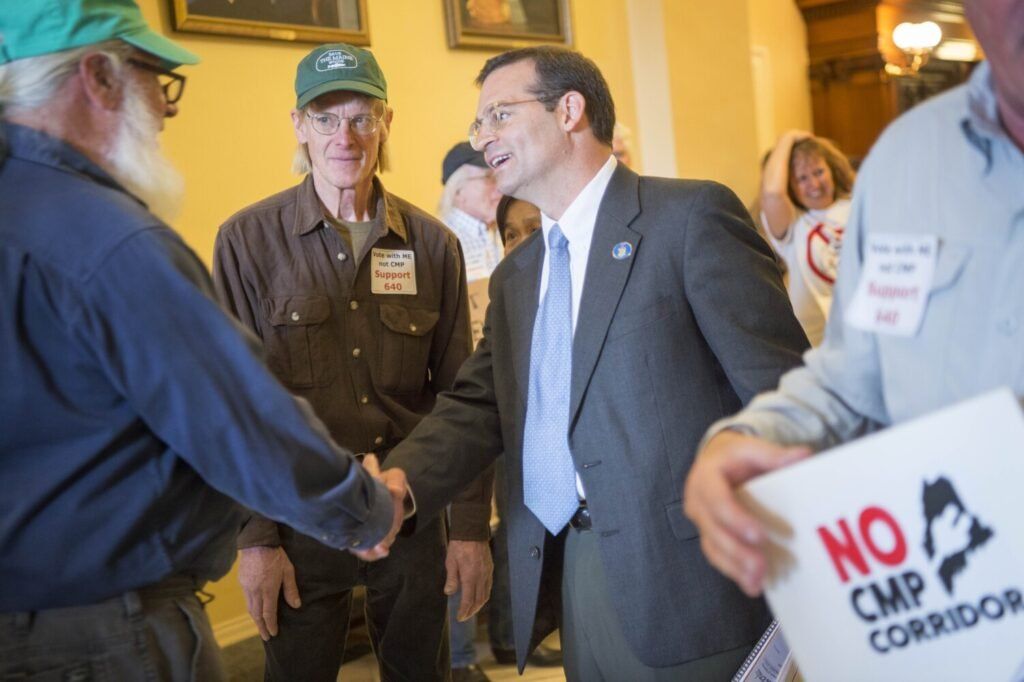 Duane Hanson, center, talks with state Rep. Seth Berry, Democrat of Bowdoin, about the proposed New England Clean Energy Connect project at the Maine State House in Augusta on June 4, 2019. Image by Michael G. Seamans. United States, 2019.
