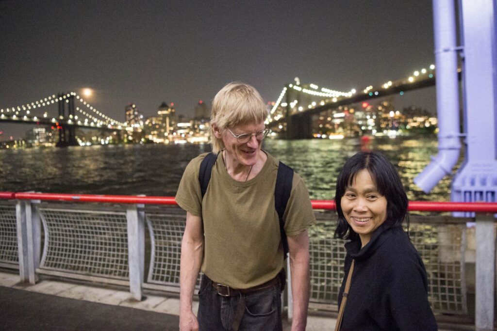 Duane Hanson, center, laughs with his partner Sally Kwan as they walk along the East River near Sally’s childhood neighborhood in Chinatown, Manhattan, on May 19, 2019. Image by Michael G. Seamans. United States, 2019.
