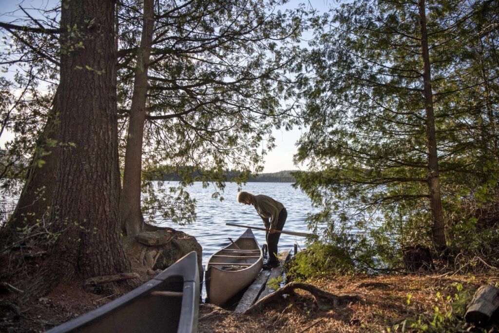 Duane Hanson prepares to launch one of his many canoes on to Whipple Pond at his homestead in the Unorganized Territories in the north woods of Maine near T5 R7 on May 26, 2019. Image by Michael G. Seamans. United States, 2019.