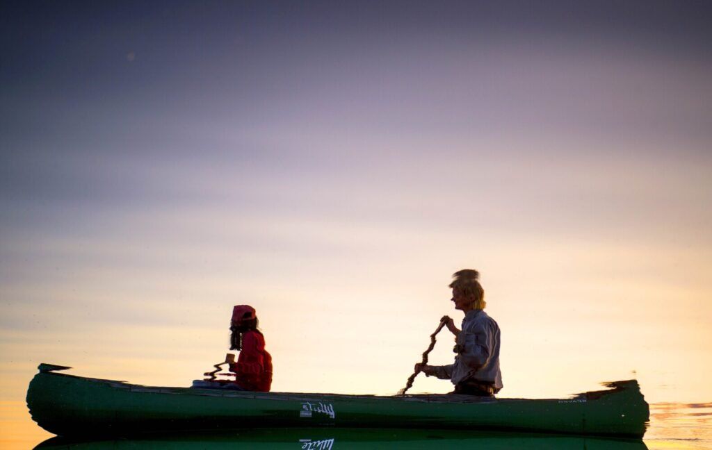 Duane Hanson and Sally Kwan are reflected in the water of Whipple Pond during a sunset paddle in the Unorganized Territories in the north woods of Maine near T5 R7 on May 27, 2019. Image by Michael G. Seamans. United States, 2019.