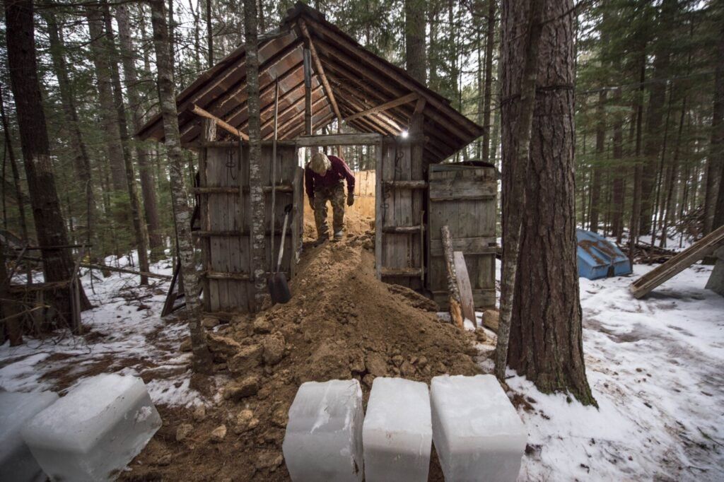 Duane Hanson cleans his ice house of old ice as he refills his stash with new blocks of ice at his homestead in T5 R7 in the Unorganized Territories on Jan. 4, 2020. Image by Michael G. Seamans. United States, 2020.