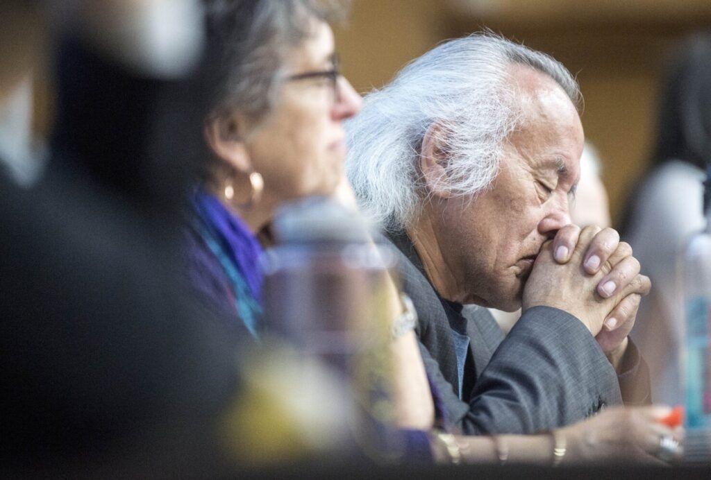 Tommy Monias from the Pimicikamak Territory in Manitoba, Canada, holds his head in his hands as a friend speaks about the impacts on their land from "mega-dam" hydropower in Manitoba during a speaking tour at Preble Hall at the University of Maine in Farmington on Nov. 25, 2019. Image by Michael G. Seamans. United States, 2019.