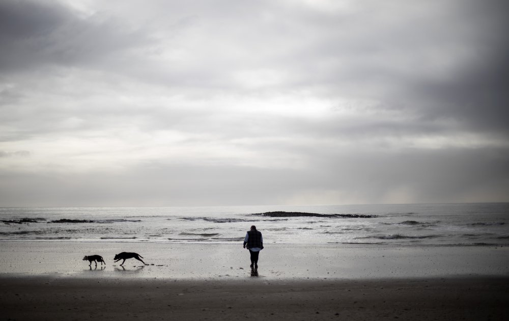 Carmall Casey walks with her dogs on the beach in Hellyer, Tasmania, Australia, Wednesday, July 24, 2019. "It's like freedom when I'm on the beach," said Casey. "I look at the footprints and different shells and it helps to release all my stress and worries." Image by David Goldman. Australia, 2019.