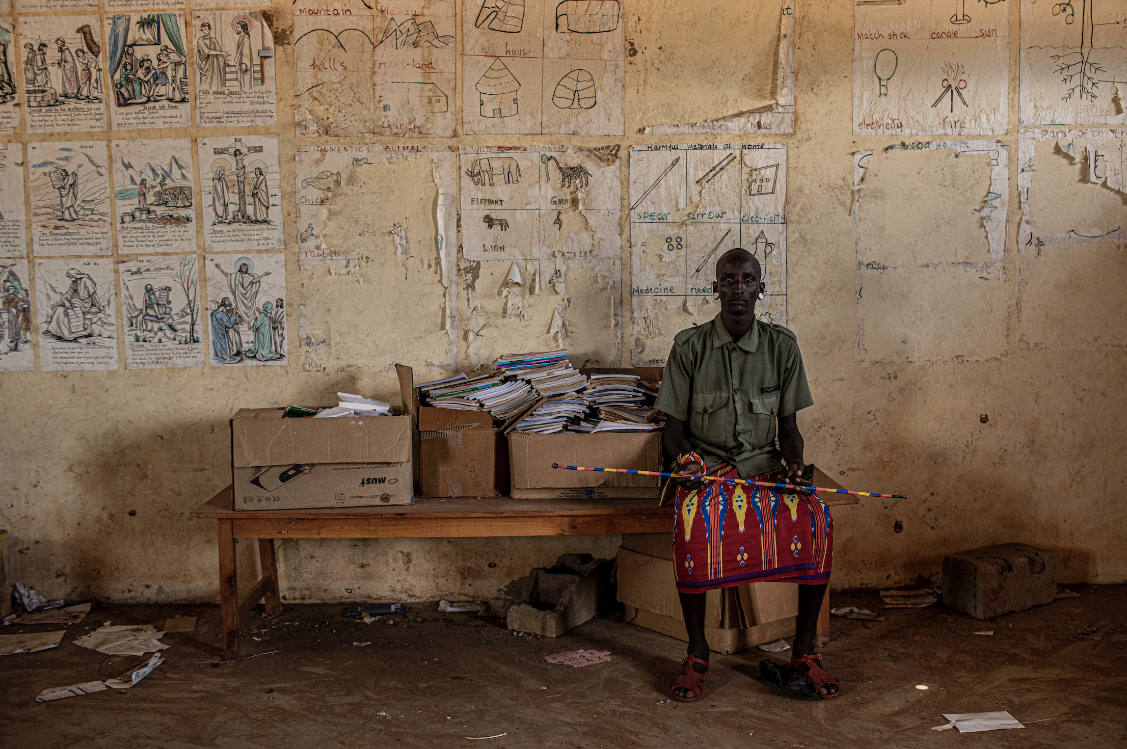 A young Rendille moran sits in a shuttered school building near the town of Laisamis in Kenya. Young men broke the windows of the school and have been living in the classrooms since the school was closed due to the COVID-19 pandemic. Image by Will Swanson. Kenya, 2020.