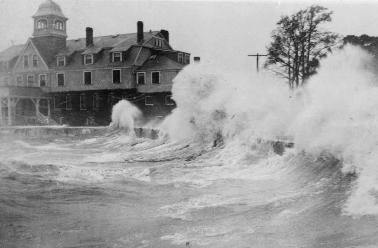 1938: Waves crashed against the Woods Hole Great Harbor waterfront and the old United States Fish Commission building during the hurricane. Image courtesy of Woods Hole Historical Museum Archives. United States, 1938.