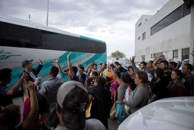 Migrants raise their hands after The Texas Tribune reporter Jay Root (back left) asked how many planned to return to Central America. Image by Miguel Gutierrez Jr. United States, 2019.