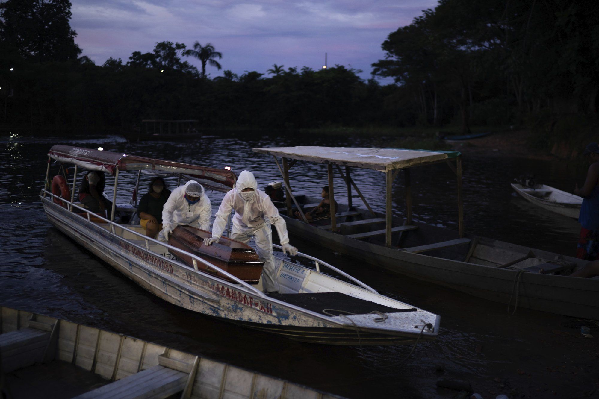 SOS Funeral workers transport by boat a coffin carrying the body of an 86-year-old woman who lived by the Negro River and is a suspected to have died of COVID-19, near Manaus, Brazil, Thursday, May 14, 2020. Image by Felipe Dana / AP Photo. Brazil, 2020.