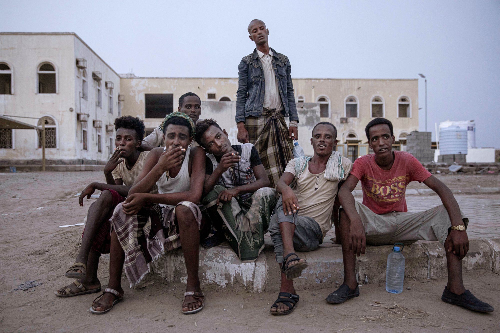 Ethiopian migrants sit together and smoke, as they take shelter in the "22nd May Soccer Stadium," destroyed by war, in Aden, Yemen. Image by AP Photo/Nariman El-Mofty.