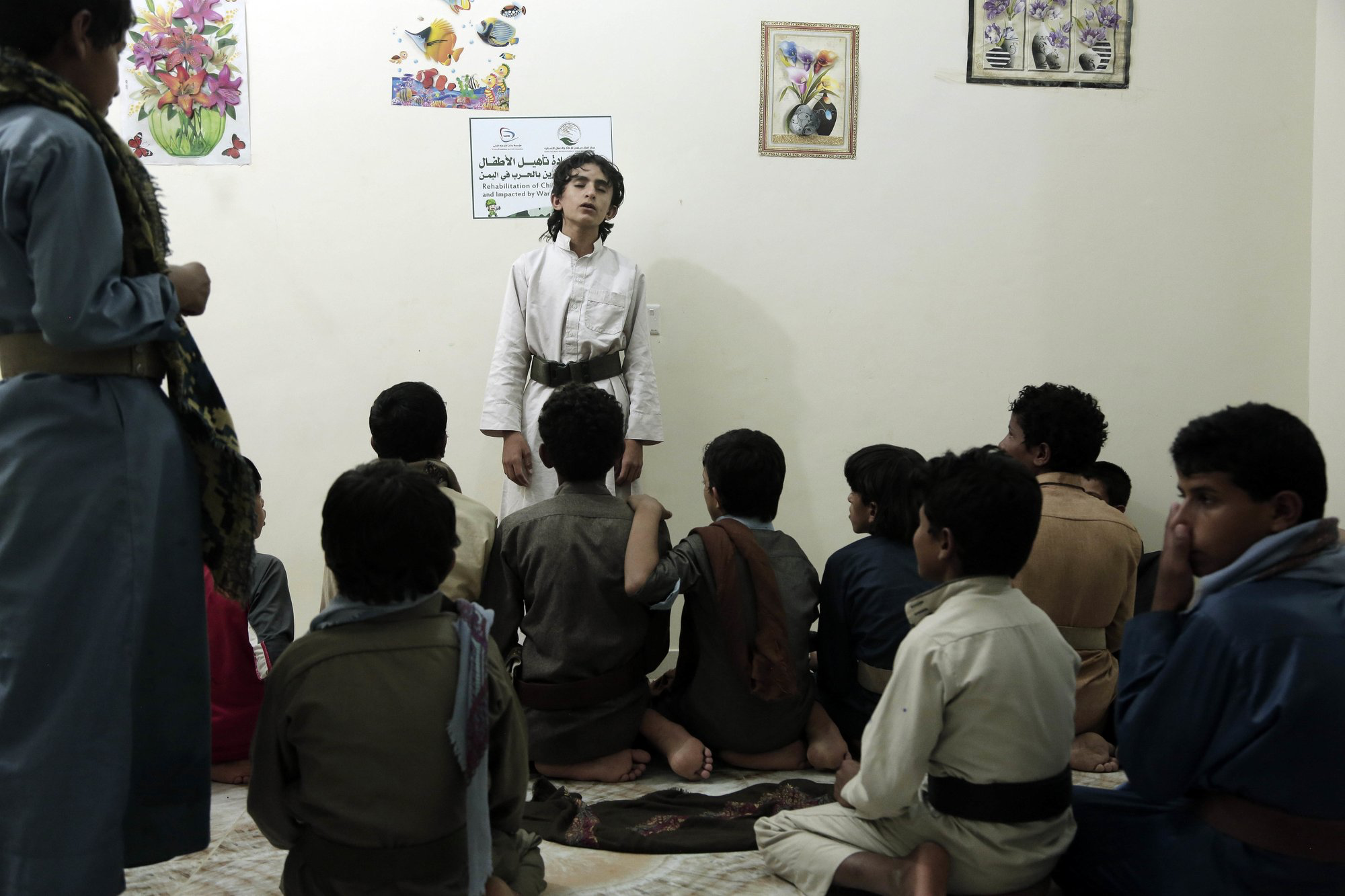 Boys recite poems during a session at a rehabilitation center for former child soldiers in Marib, Yemen, in this July 25, 2018, photo. The Houthi rebels have enlisted some 18,000 child fighters over the course of the 4-year-old civil war, according to one Houthi official. Their experiences in combat, including seeing bodies of the dead and charging into battle as missiles explode, have left many of the boys traumatized. Image by Nariman El-Mofty / AP News. Yemen, 2018.