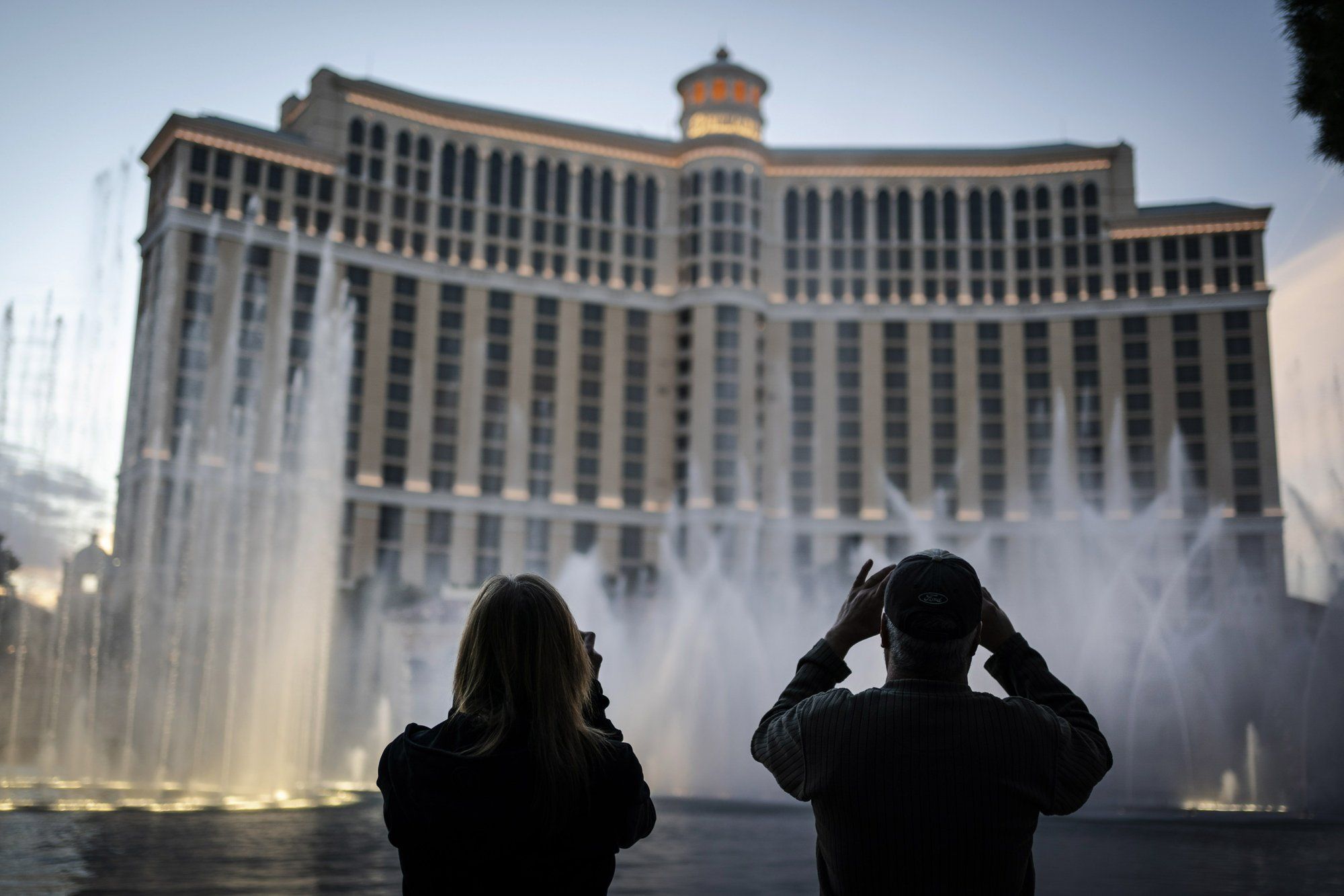 People are silhouetted as they take photos of the fountains at the Bellagio hotel-casino along the Las Vegas Strip, Wednesday, Nov. 11, 2020. Image by Wong Maye-E / AP Photo. United States, 2020.