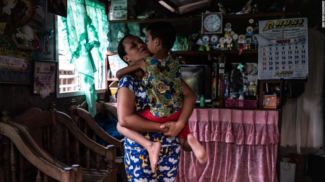 April Abrias hugs her son, Yohan, inside their home after she has disinfected and changed her clothes. Image by Xyza Cruz Bacani. Philippines, 2020.