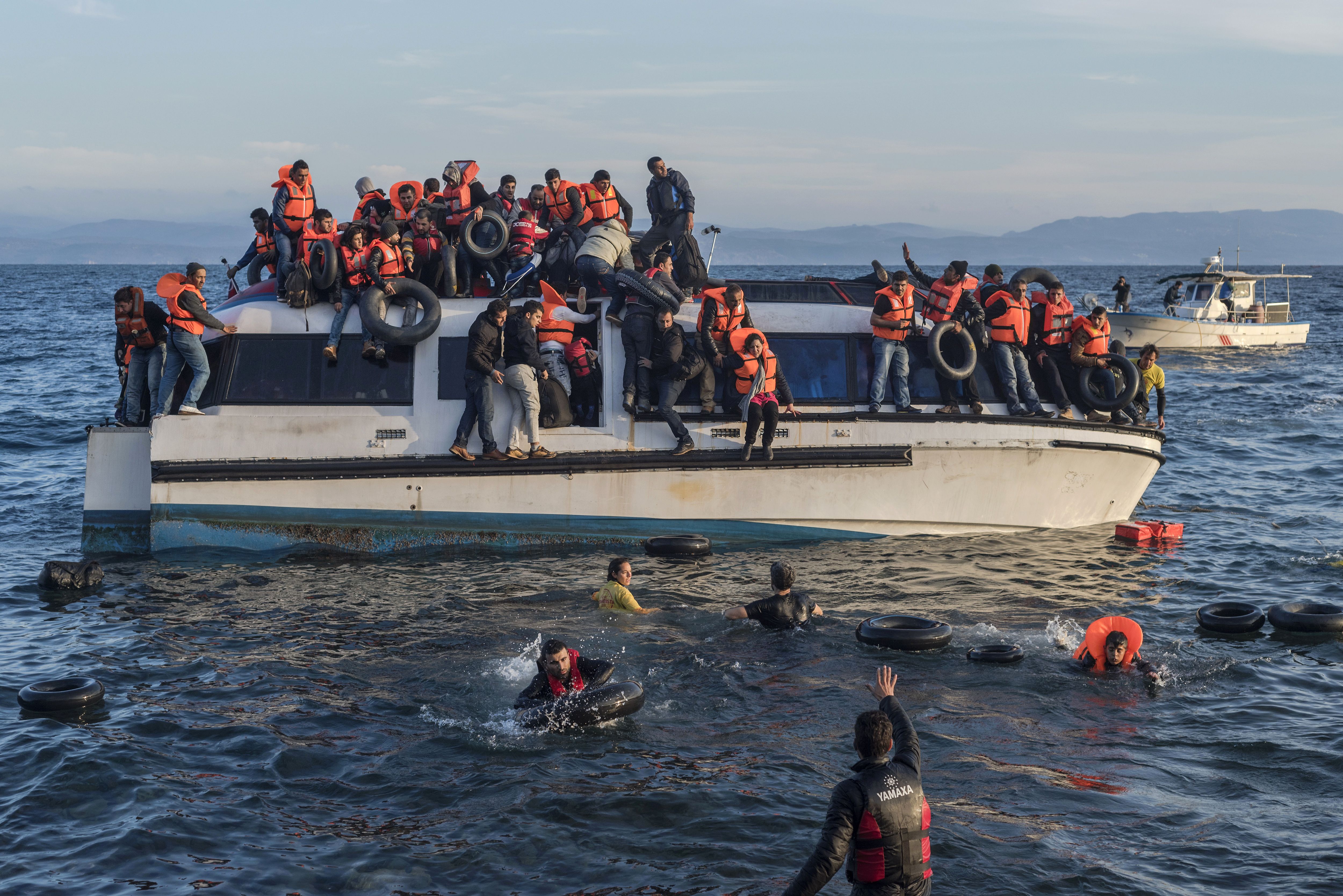 Syrian and Iraqi refugees arrive from Turkey to Skala Sykamias, Lesbos island, Greece. Spanish volunteers (life rescue team with yellow-red clothes) are from "Proactiva open arms." Image courtesy Ggia / Creative Commons 4.0.