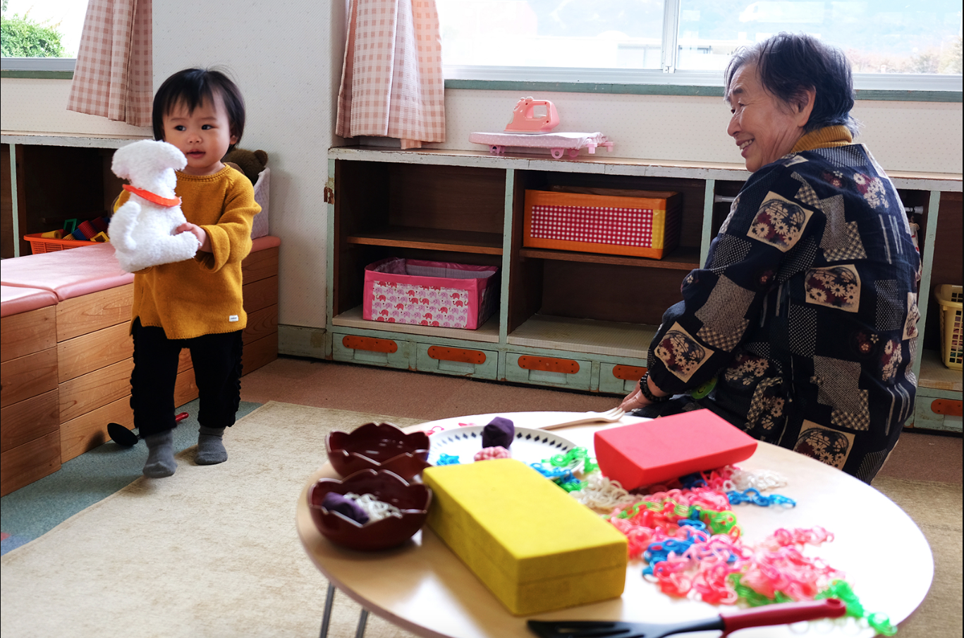 An older volunteer watches over a busy mother's child. Image by Emiko Jozuka. Japan, 2018.