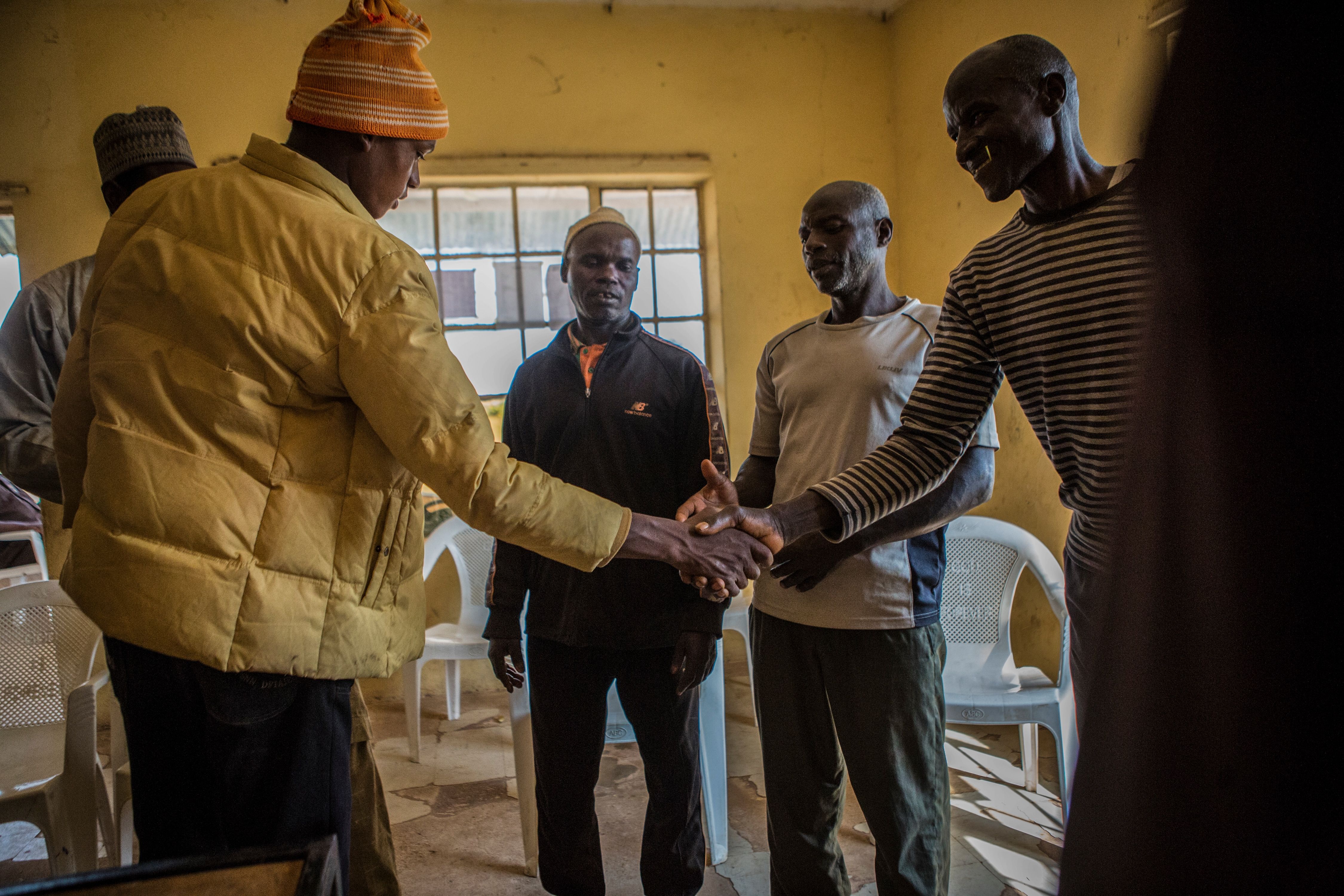 Cattle herder Muhammad Yusuf, 20, left, shakes hands with farmer Amos Lenji in Barkin Ladi in October as volunteer peacekeepers mediate a dispute about cattle intruding on farmland. Yusuf took responsibility for another herder whose cattle had trampled Lenji’s crops. Image by Jane Hahn. Nigeria, 2018.