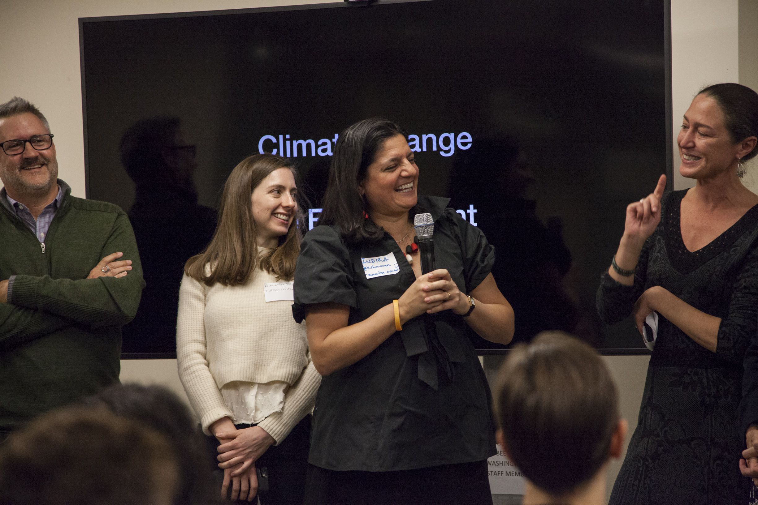 Pulitzer Center Executive Editor laughs with Managing Director Nathalie Applewhite during staff introductions. Behind them are Pulitzer Center staff members Steve Sapienza and Katherine Doyle. Image by Jin Ding. United States, 2018.