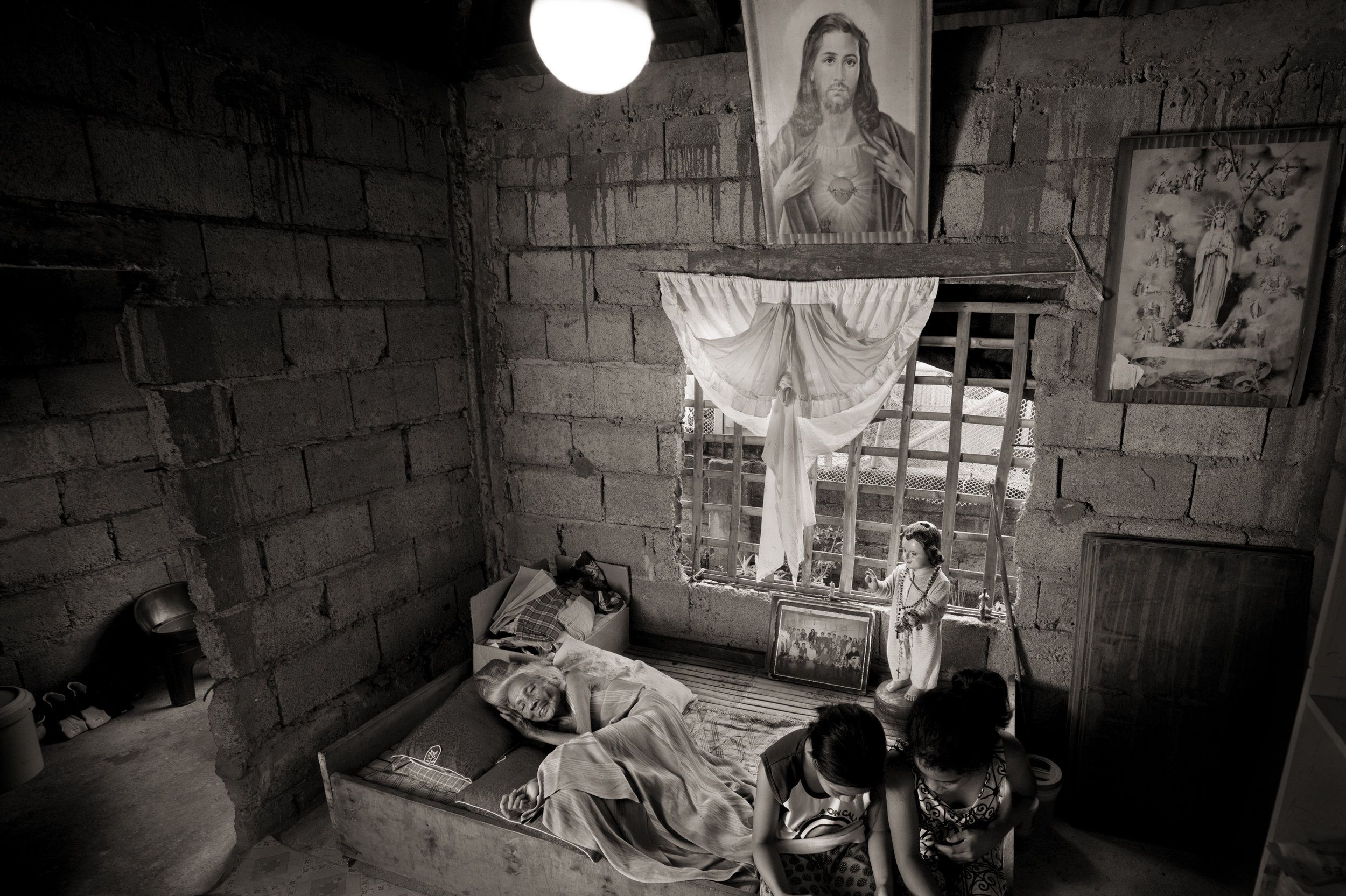 Juliana dela Cruz, 92, lies at her home in Roxas City on May 27, 2019. She died Sept. 12 of that year. In 1998, she testified: "At the garrison, they imprisoned me in a room. The cook was the only one who could give me food. The only other ones I saw were the three soldiers who came into my room every night and raped me three to five times a night in the course of one month." Image by Cheryl Diaz Meyer. Philippines, 2019.