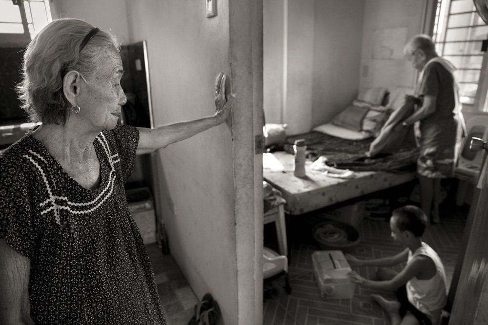 Narcisa Claveria, watches husband, Anaceto, and their great-grandson as he wakes up from a nap. At age 12, Narcisa was dragged from her home by Japanese soldiers and forced to serve as a sex slave in a garrison for 1 1/2 years. At a time when the experience was seen as a mark of shame, her husband encouraged her to share her story and told her: "I am not repulsed by you." Image by Cheryl Diaz Meyer. Philippines, 2019.
