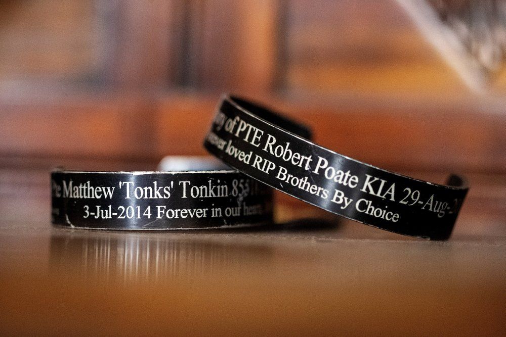 Bracelets remembering Matthew Tonkin, left, and his friend and fellow soldier, Robert Poate, sit on a table at the Tonkin home in Perth, Australia, Sunday, July 21, 2019. Matthew was suffering from post-traumatic stress disorder, a result of the horrors he experienced in Afghanistan, including the death of his best friend, Poate. He was also suffering from a growing addiction to opioids. Image by David Goldman. Australia, 2019.