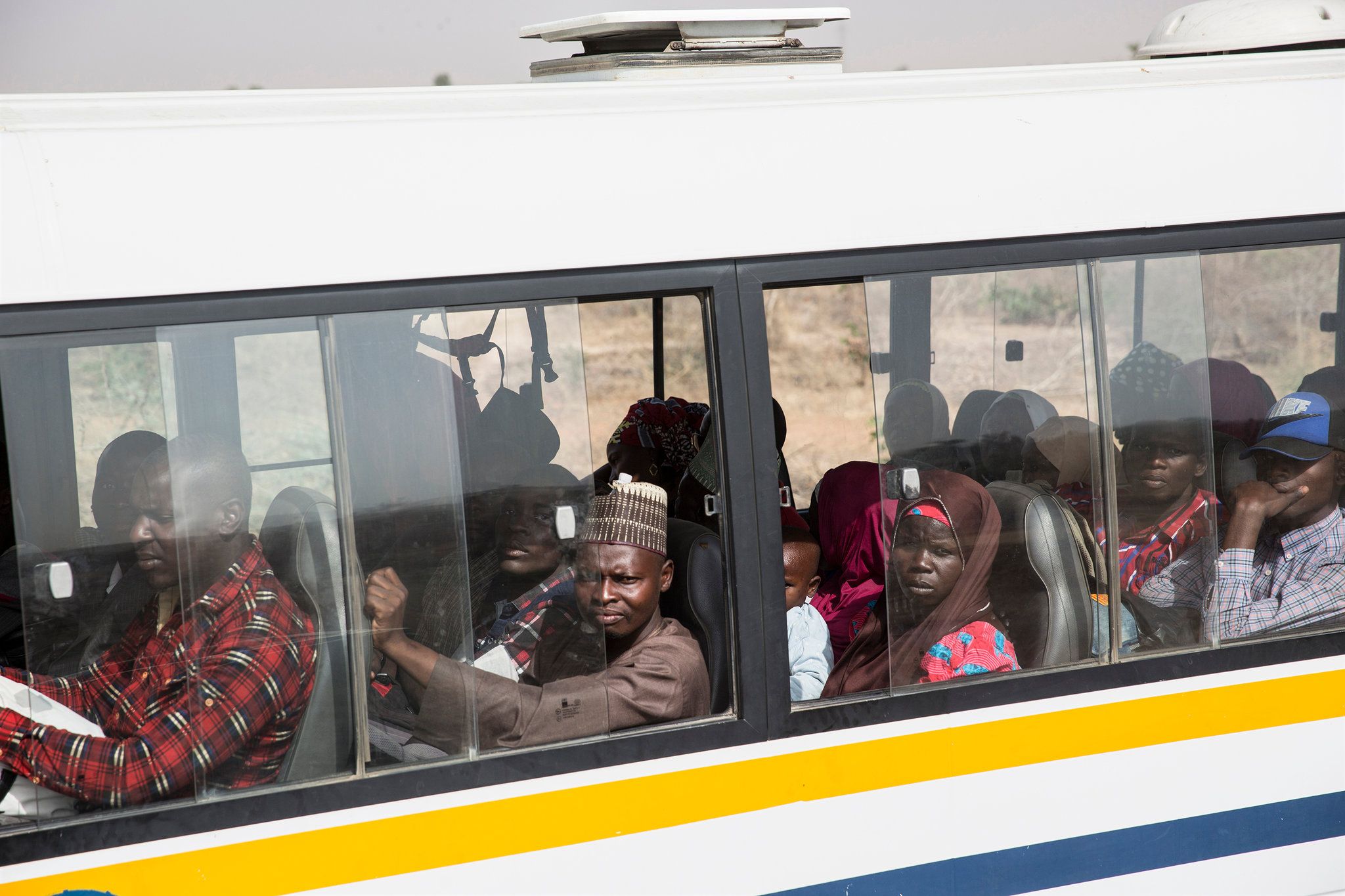 Traveling by bus, rather than in the back of a truck, is a more expensive but more comfortable way to make the risky convoy trip. Image by Glenna Gordon. Nigeria, 2017.