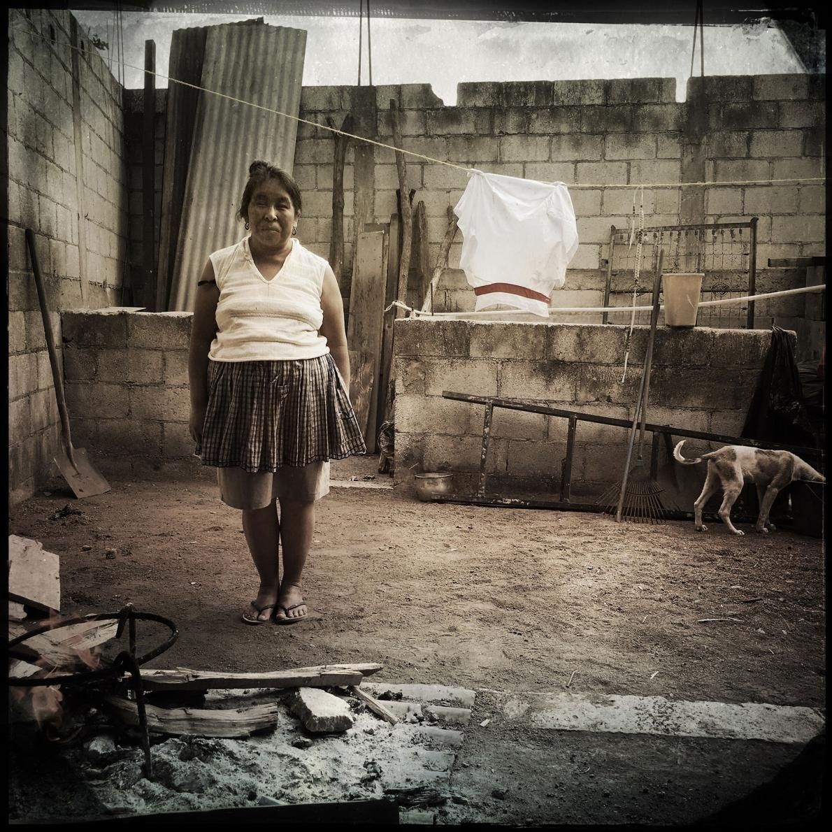 San Antonio Aguas Calientes: Maria Ermelinda Lopez Mendoza stands in her cooking area in her courtyard. She can’t afford a stove, so she cooks over this makeshift open flame. Image by Lynn Johnson. Guatemala, 2017.