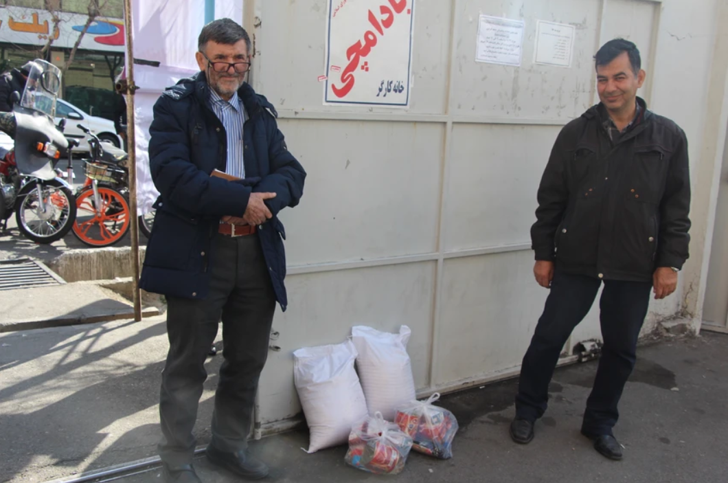 Hasan Muhamdi, left, collects his subsidized food package. Photo by Reese Erlich. Iran, 2020.