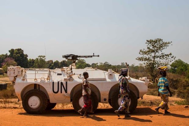 Women walk past a UN armoured personnel carrier at the camp’s entrance. Image by Jack Losh. Central African Republic, 2019.