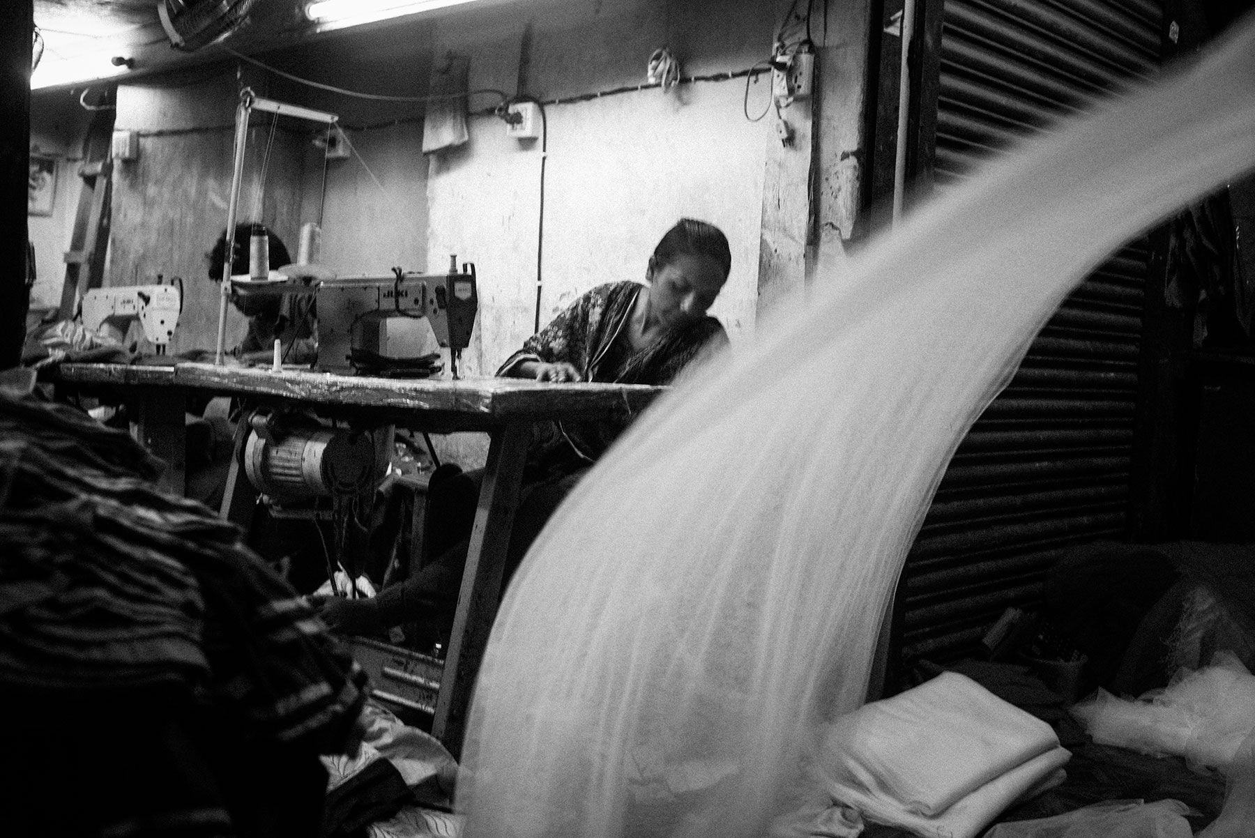 A garment worker sews at her station in a factory in Dhaka. Image by Jošt Franko. Bangladesh, 2016.