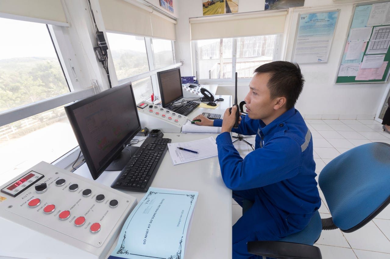 A worker monitors the blending of feed from an elevated control room at TH Milk's operations in Nghia Son, Vietnam. The company has 200 workers dedicated to the production of 500,000 tons of animal feed for their 40,000 head dairy operations. Image by Mark Hoffman. Vietnam, 2019. 