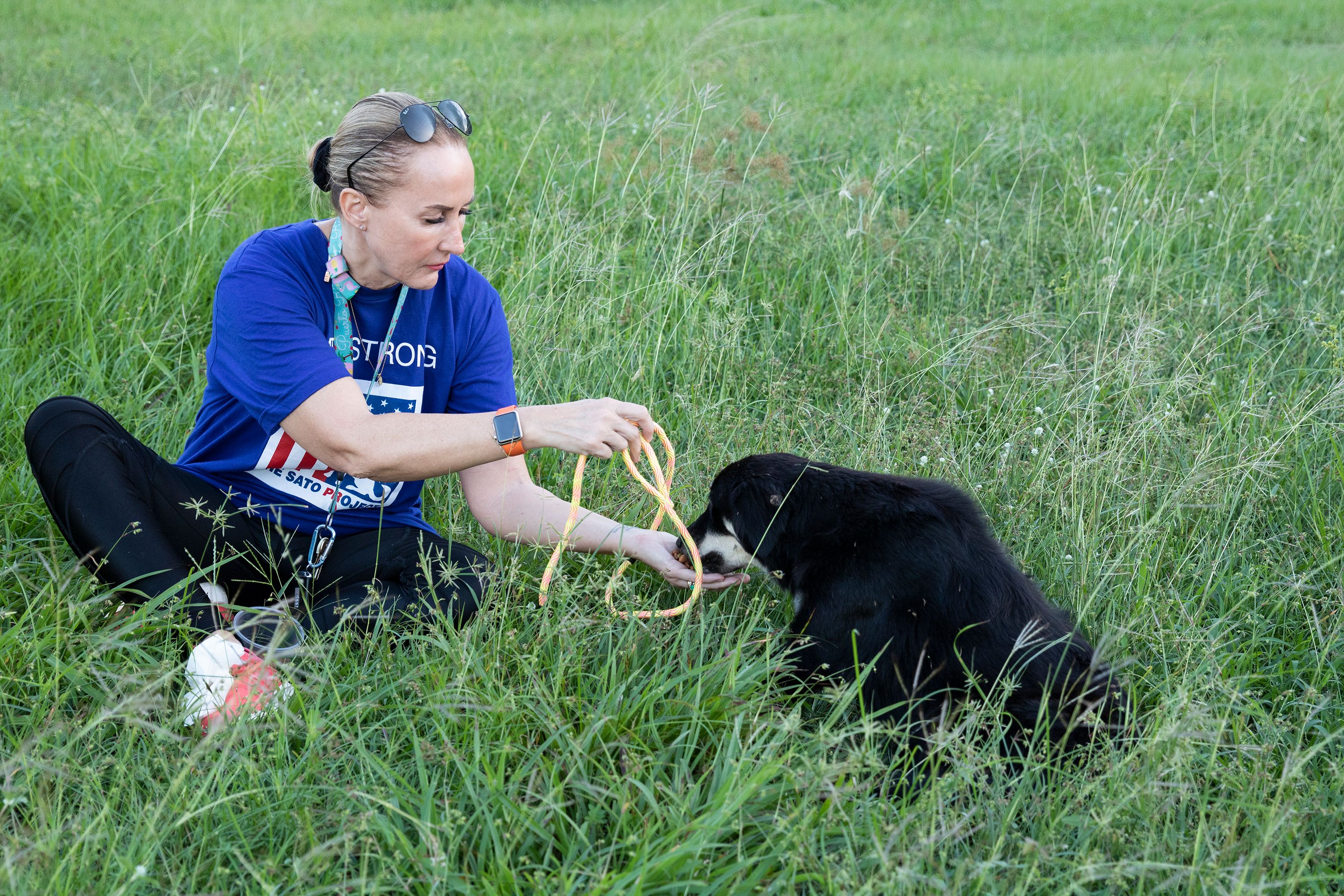 Using the food as a distraction, Beckles places her hand through the leash to loop it around the dog’s neck. Image by Jamie Holt. United States, 2019.