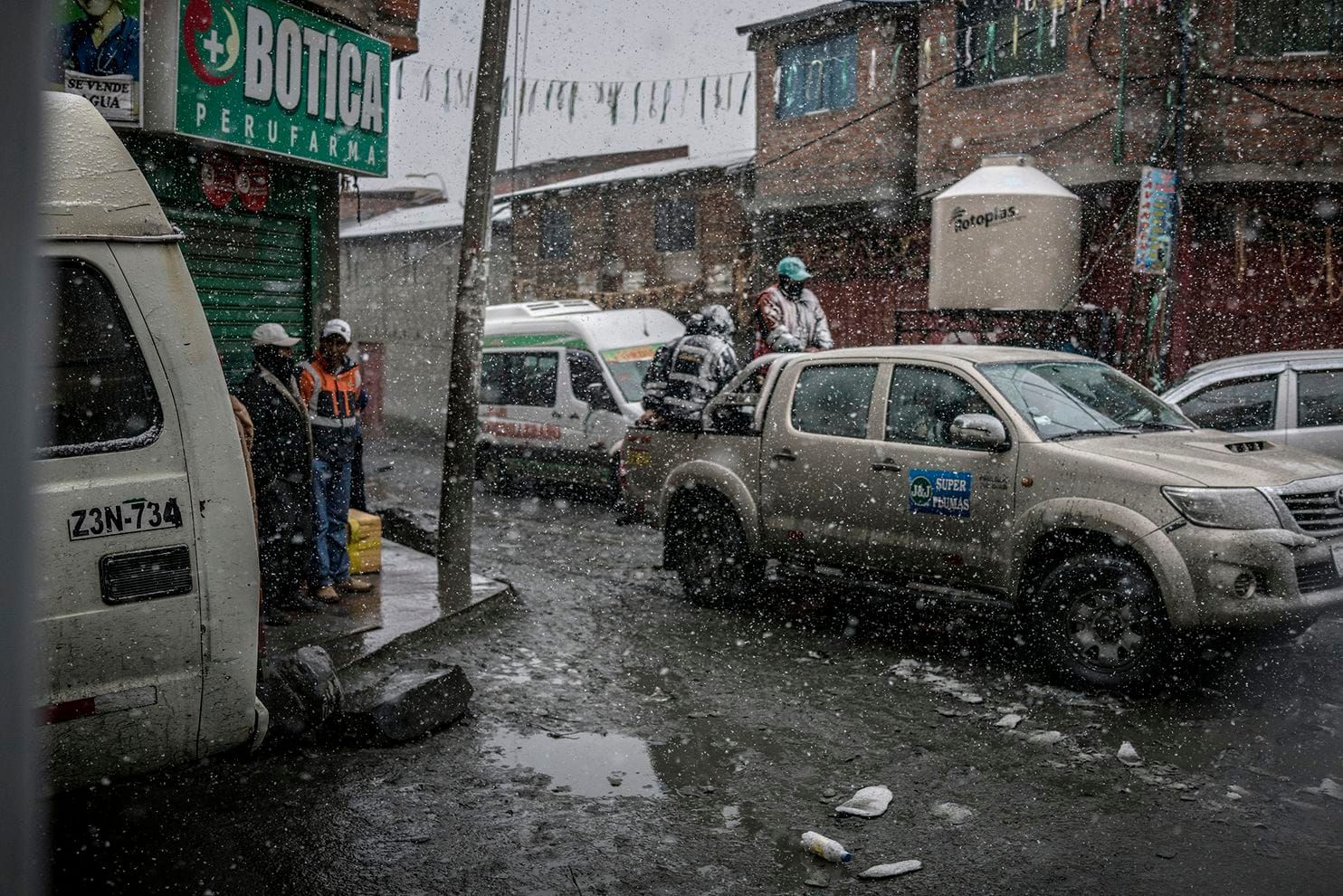 Miners brave snow in the back of a truck on the streets of La Rinconada, a gold-mining town in the Peruvian Andes. Peru, 2019. Image by James Whitlow Delano.
