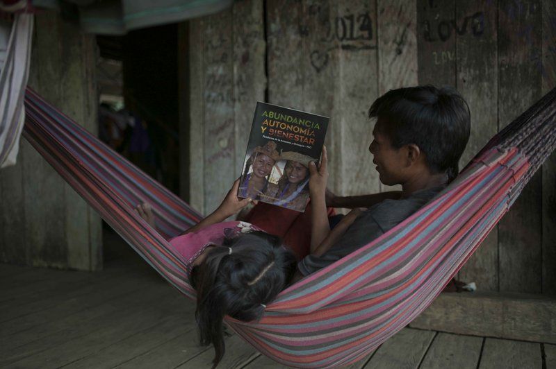 A girl and her father read a magazine about the knowledge and customs of the indigenous peoples. Image by Luis Ángel. Colombia, 2019.