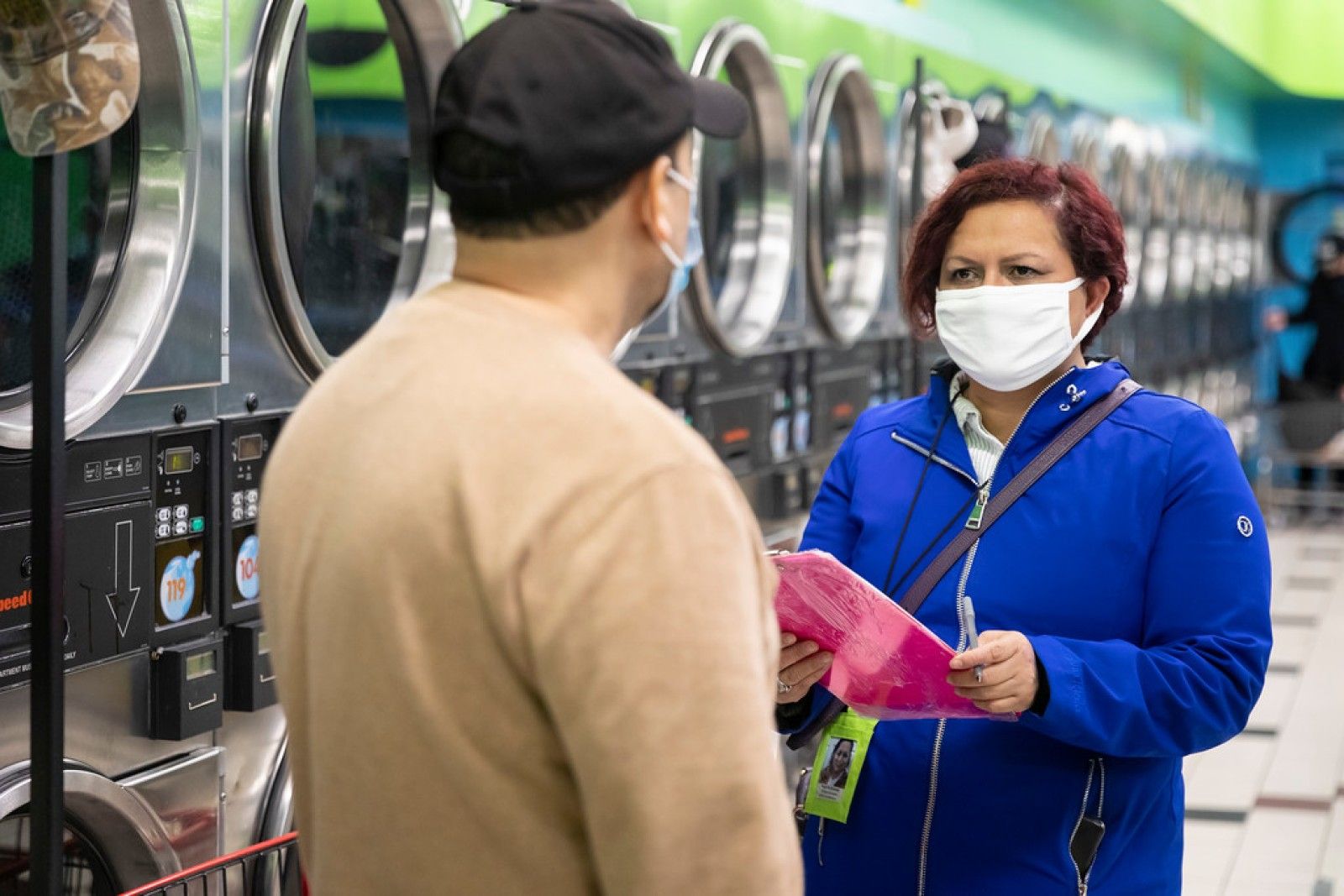 Margarita Sanchez, right, conducts a COVID-19 survey with a patron at a Belmont Cragin laundromat. Manuel Martinez / WBEZ News.
