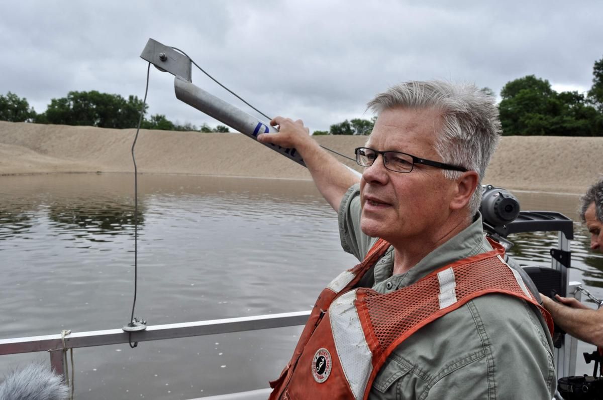 Jon Hendrickson of the Army Corps of Engineers stands in a boat near piles of dredged Mississippi River sediment on Crater Island, Wisconsin. Image by Tristan Baurick / NOLA.com | The Times-Picayune. United States, 2019.

