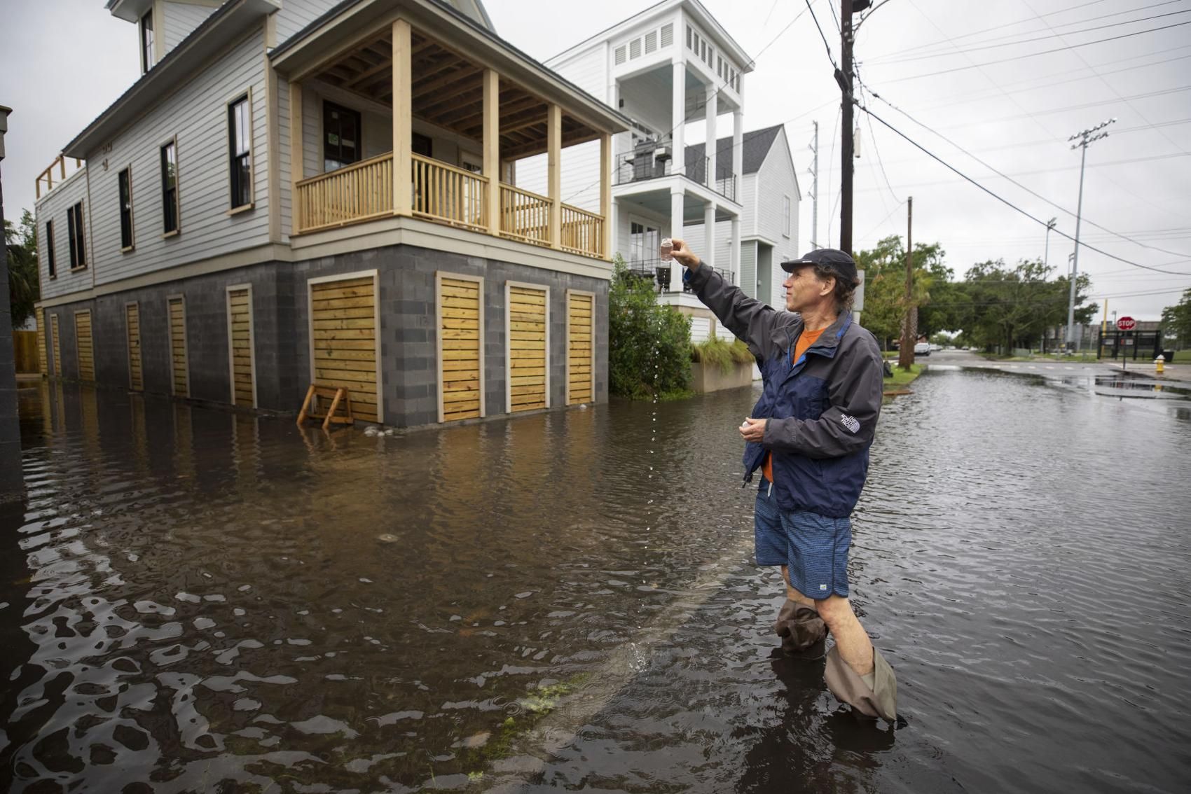 Tony Bartelme, projects reporter for The Post and Courier, collects a sample of flood water from Line Street in downtown Charleston after a heavy rain on Wednesday, May 27, 2020. Image by Lauren Petracca / Post and Courier. United States, 2020.