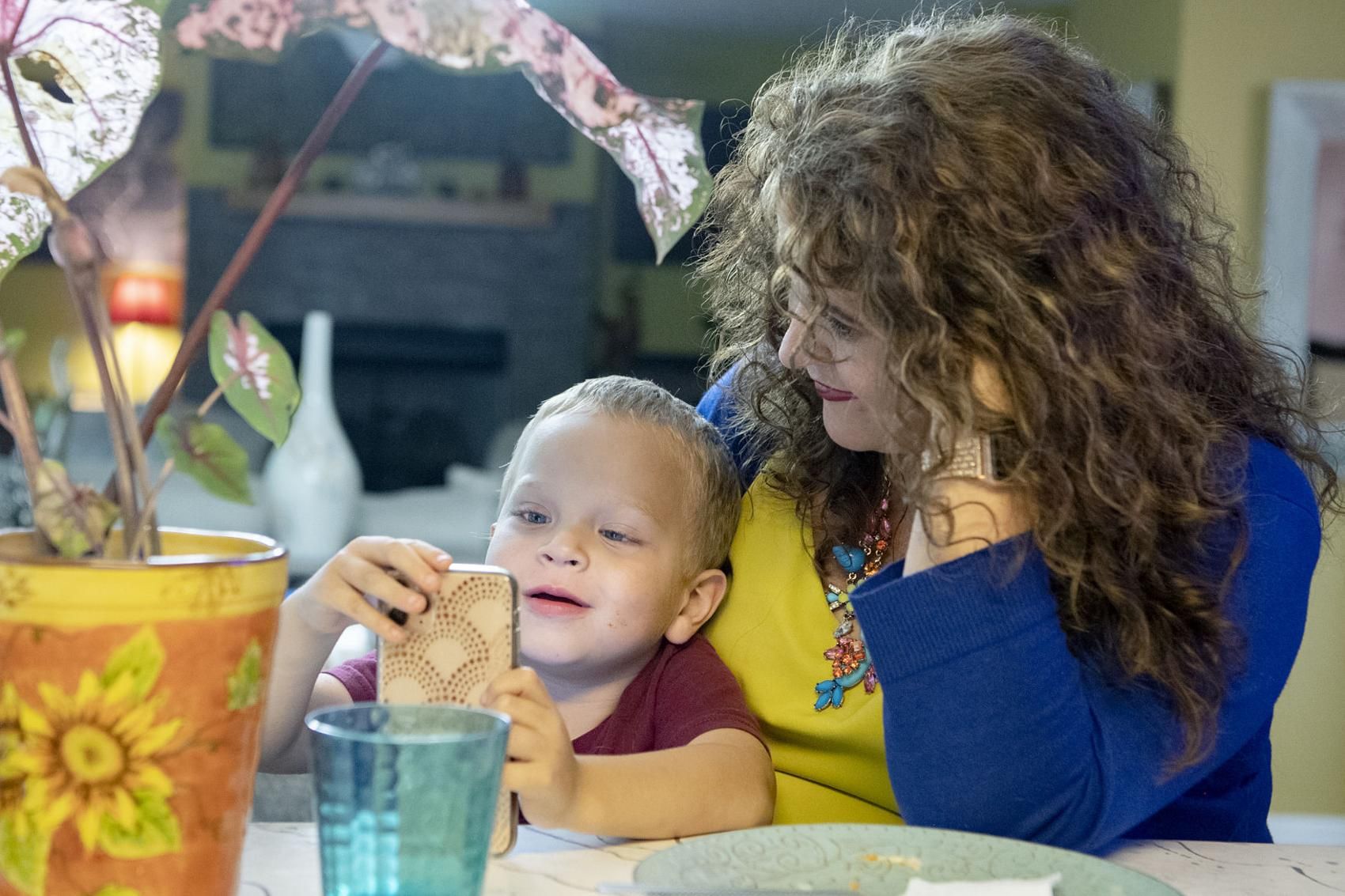 Crystal Camacho plays a game on her phone with her son, Elias, 4, at the kitchen table of their home in Swannanoa on June 30. Image by Angeli Wright/Asheville Citizen Times/North Carolina News Collaborative. United States, 2020.

