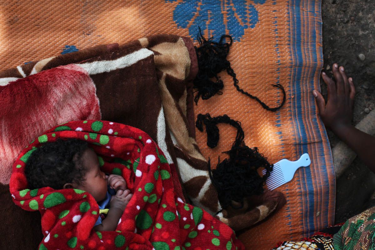 The one-month-old baby girl of a mother, 16, who was held by rebel soldiers, is sleeping on a mat in their compound, outside Yambio. The mother was made a second wife for one of the soldiers, but other men were sleeping with her, too. She does not know who the father is, but she loves the child. 'My grand-mother welcomed me when I came back, and the child when she was born. But some neighbours were scared. They said I had the mindset of the people in the bush. I was made to kill and maybe I would do it again.' She’s learning tailoring but after, would like to go back to primary school. She says till today, she doesn’t dare to go back to the fields because she is scared of being abducted again. Image by Andreea Campeanu. South Sudan, 2018.