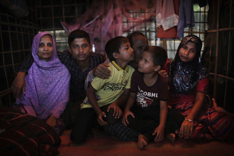 Bodru Duza, 52, third from right, kisses his sons as he sits for a portrait with members of his family in a tent in Kutupalong refugee camp in Bangladesh. Image by Wong May-E. Bangladesh, 2017.