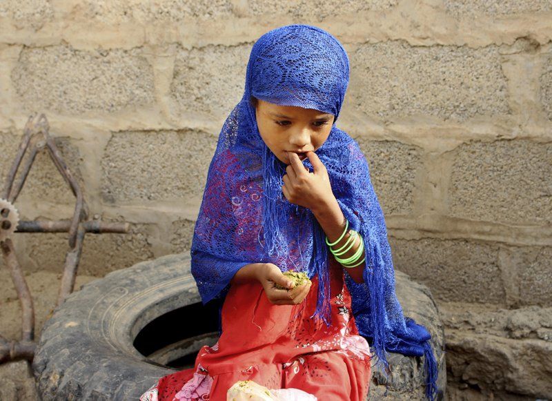 A girl eats boiled leaves from a local vine to stave off starvation. Image by Hammadi Issa/AP Photo. Yemen, 2018.