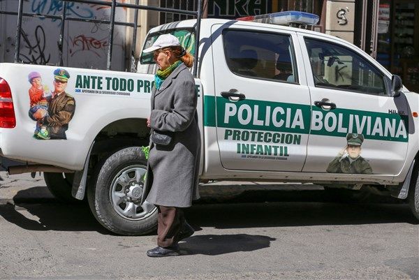 A woman walks past a police truck marked "child protection" in La Paz, where a 2014 law allows children to work as young as age 10. Government supporters say the law protects children and gives them a voice. Image by Tracey Eaton. Bolivia, 2017.