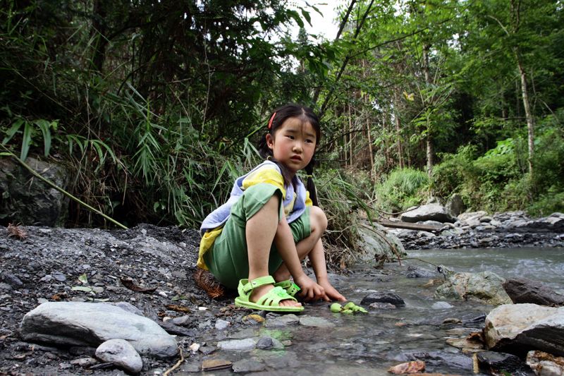 A young girl plays in the water in the mountainous forests of northern Sichuan.