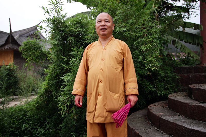 A Buddhist monk stands in front of a bamboo plant at the "Bamboo Sea."          