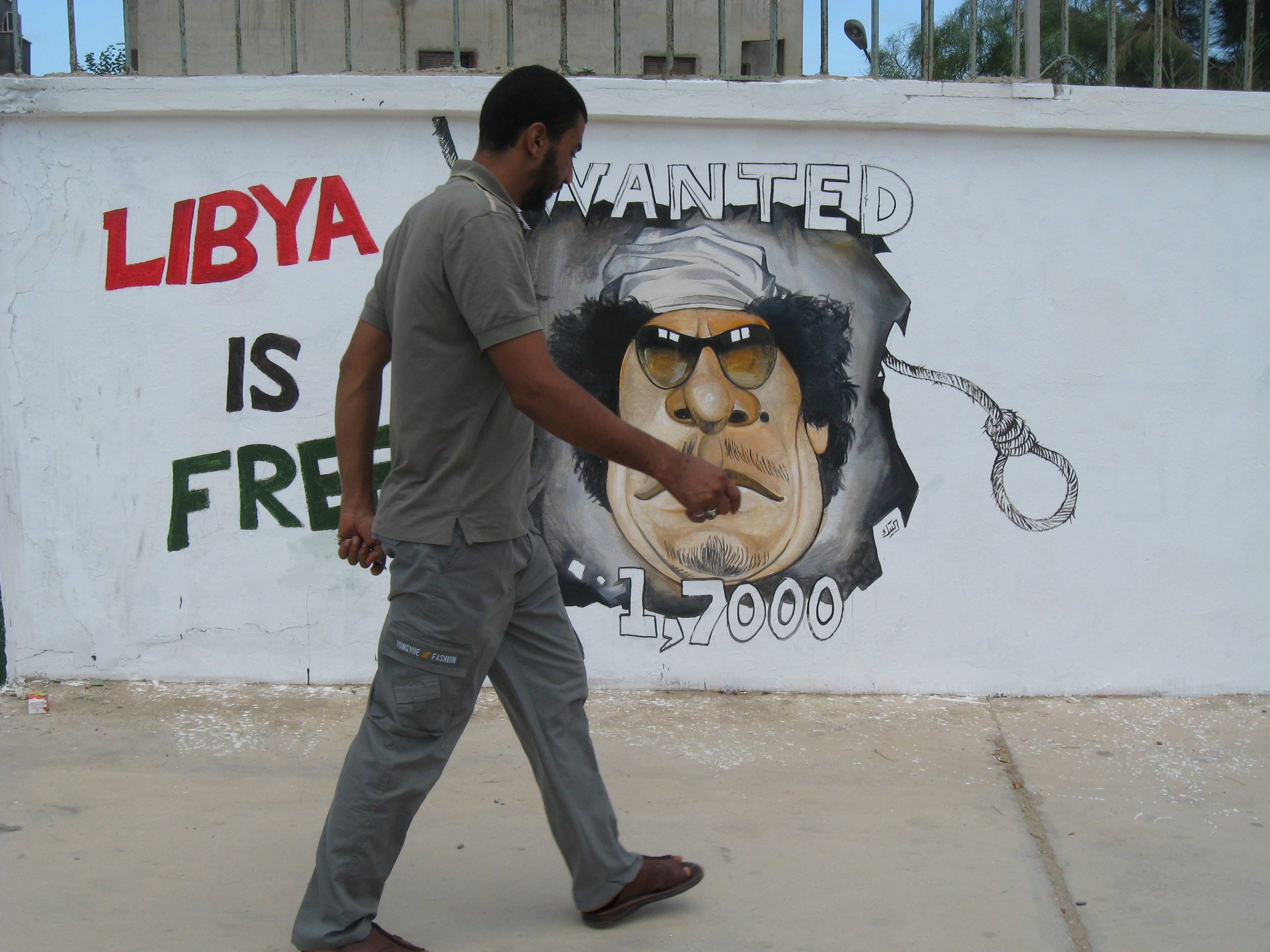 A man walks by one of the countless cartoons of Qaddafi. Libya, 2011.