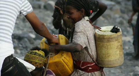 A girl carries cans of water. Image by Alex Stonehill. Ethiopia, 2008.