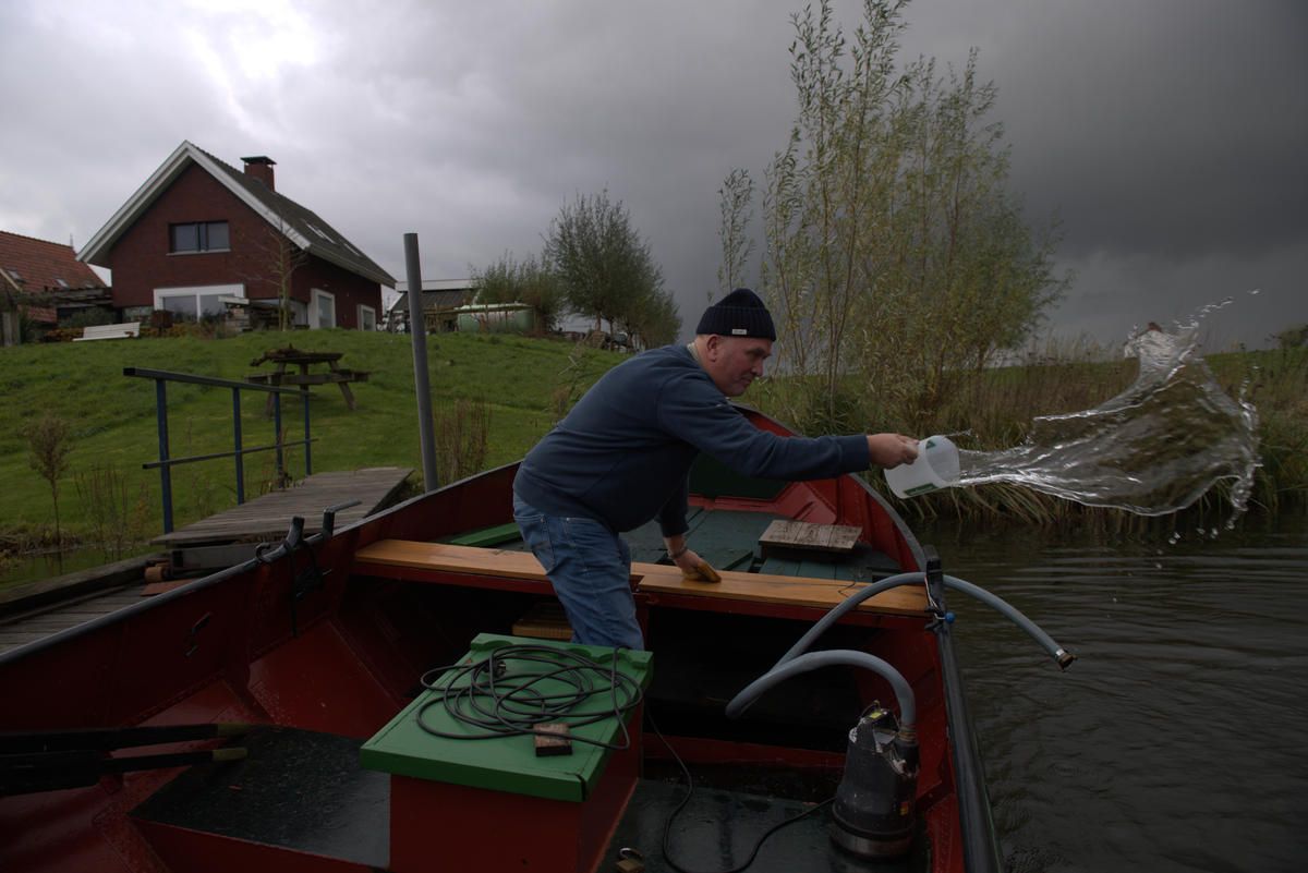 Vic Gremmer bails out his wooden boat before a rain storm in South Holland. Gremmer agreed to relocate his home as part of a program that makes room for for rivers to flood safely. Image by Chris Granger / Times-Picayune / The Advocate. Netherlands, undated.
