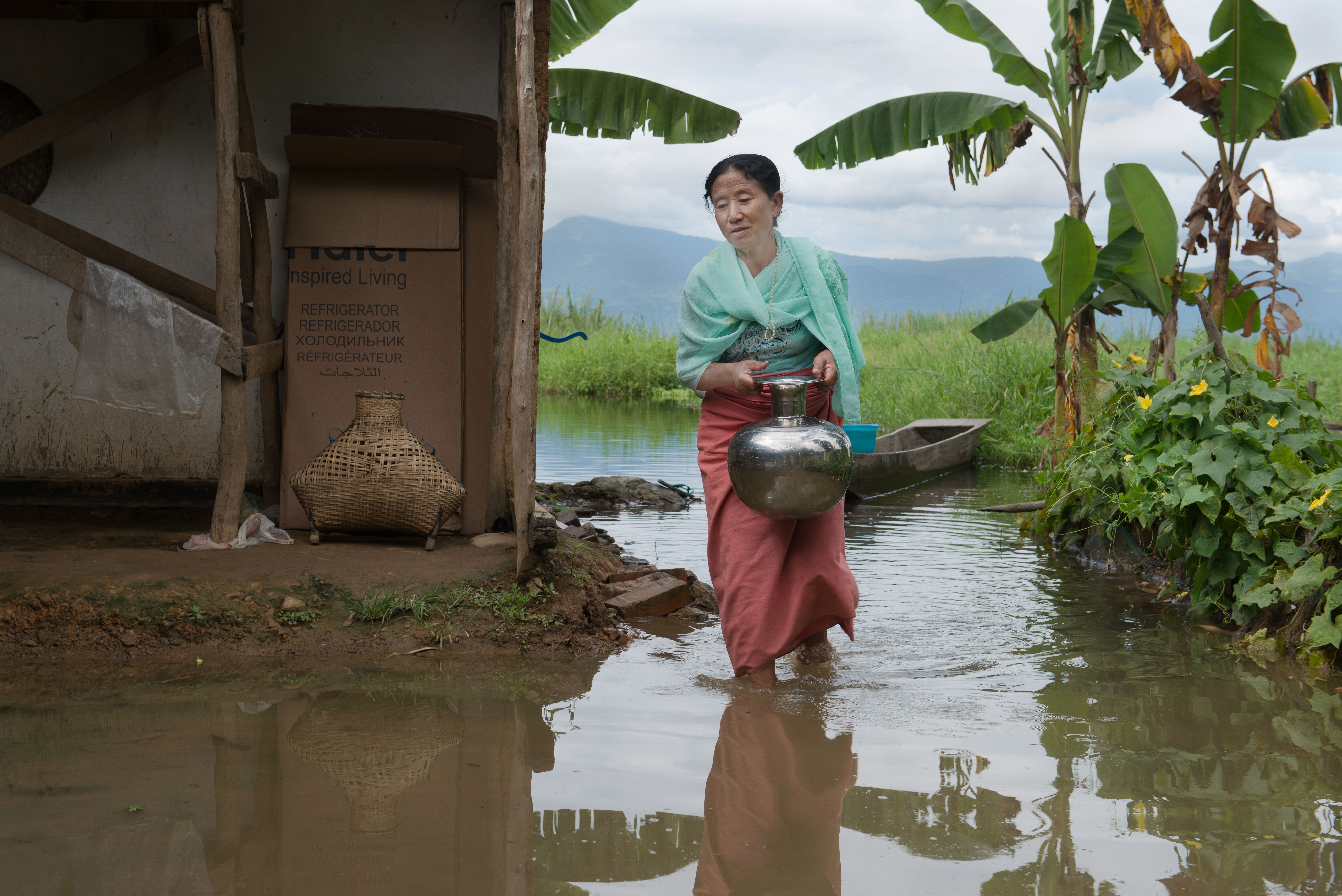Muktarei Oinam wades through the flooded front yard of her home in the village of Thanga in the Loktak area of Manipur. Image by Neeta Satam. India, 2017.