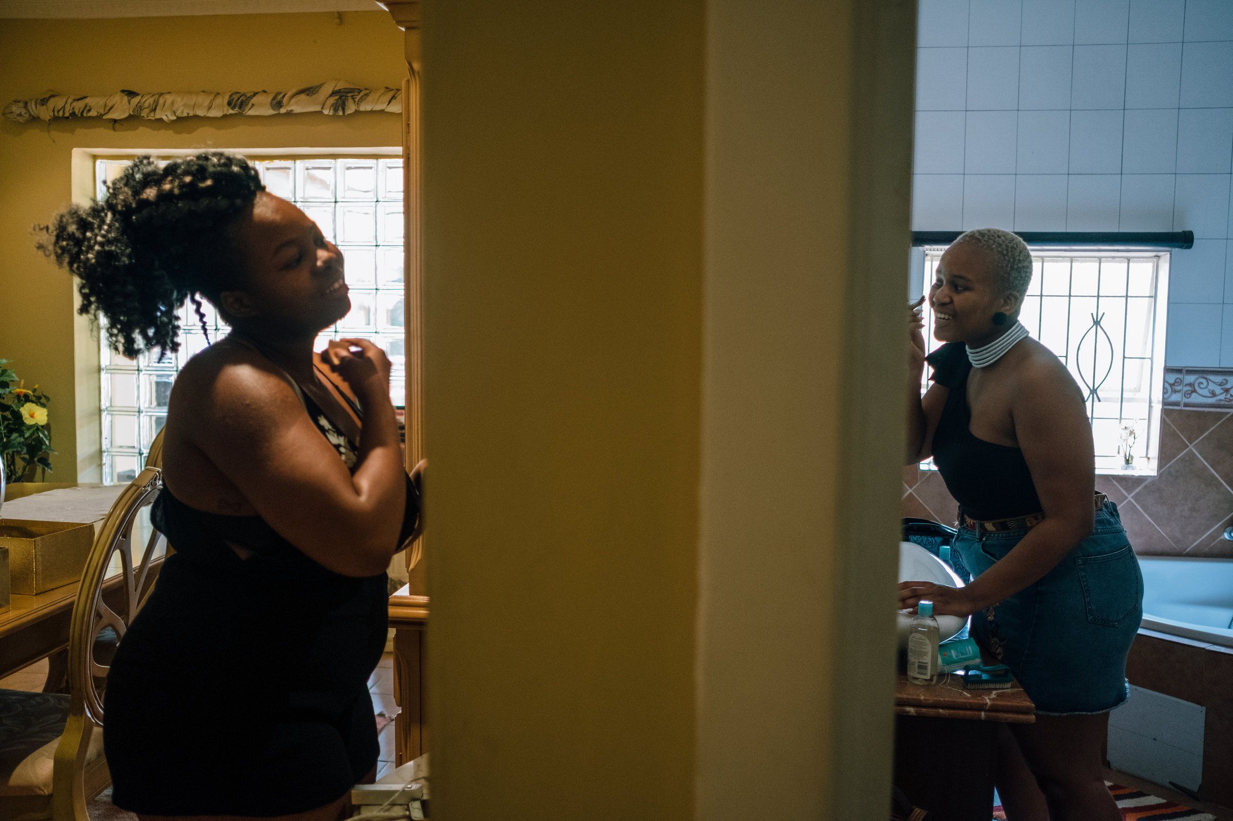 Cousins Mpho Rantao, 21, (left) and Ntaoleng Mokotini, 21, apply makeup in preparation for the Afropunk Joburg event later that day. Image by Melissa Bunni Elian. South Africa, 2017.