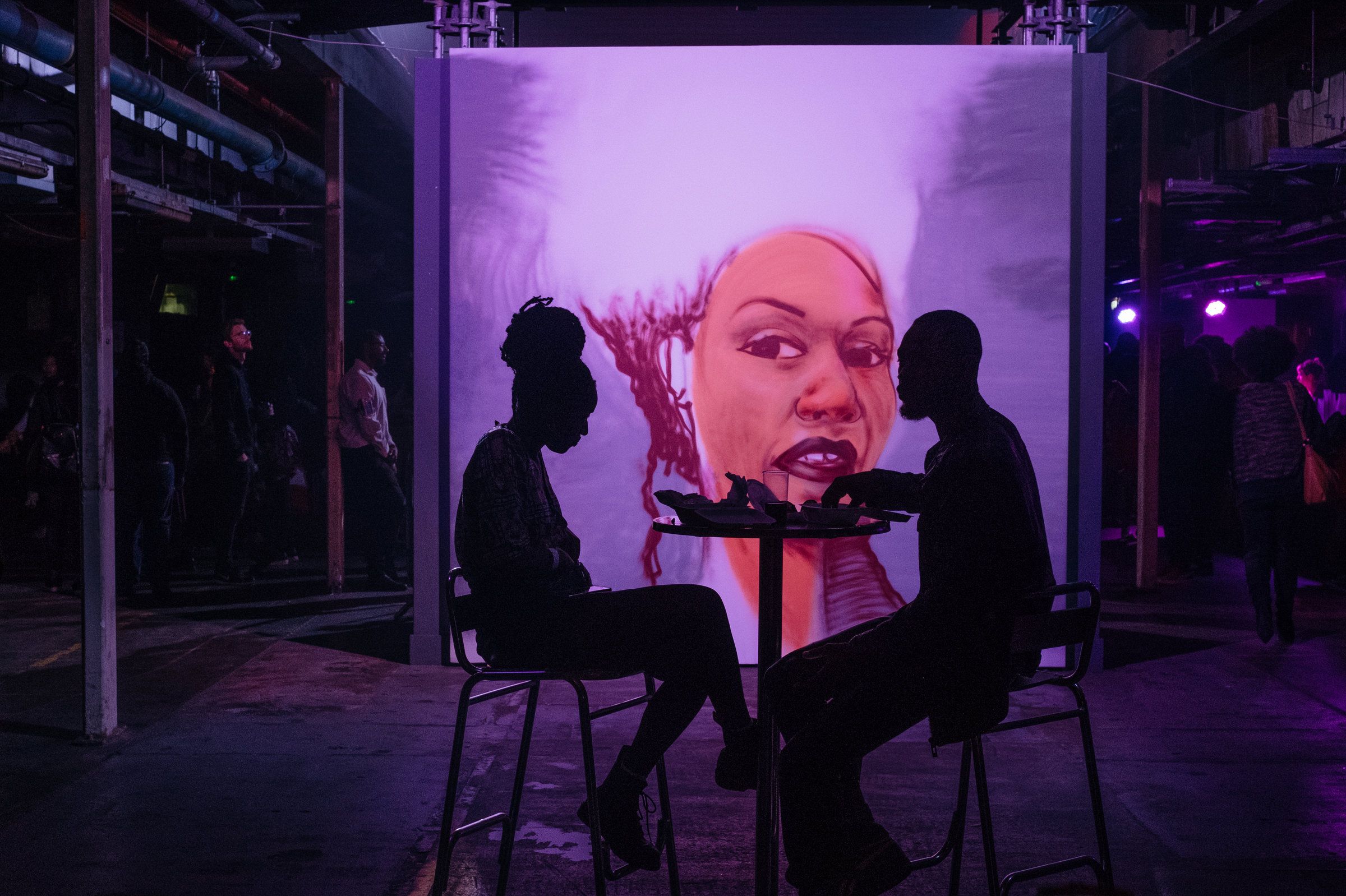 A mural illuminates an intimately lit lounge area at the Afropunk London festival in July. Image by Melissa Bunni Elian. South Africa, 2017.