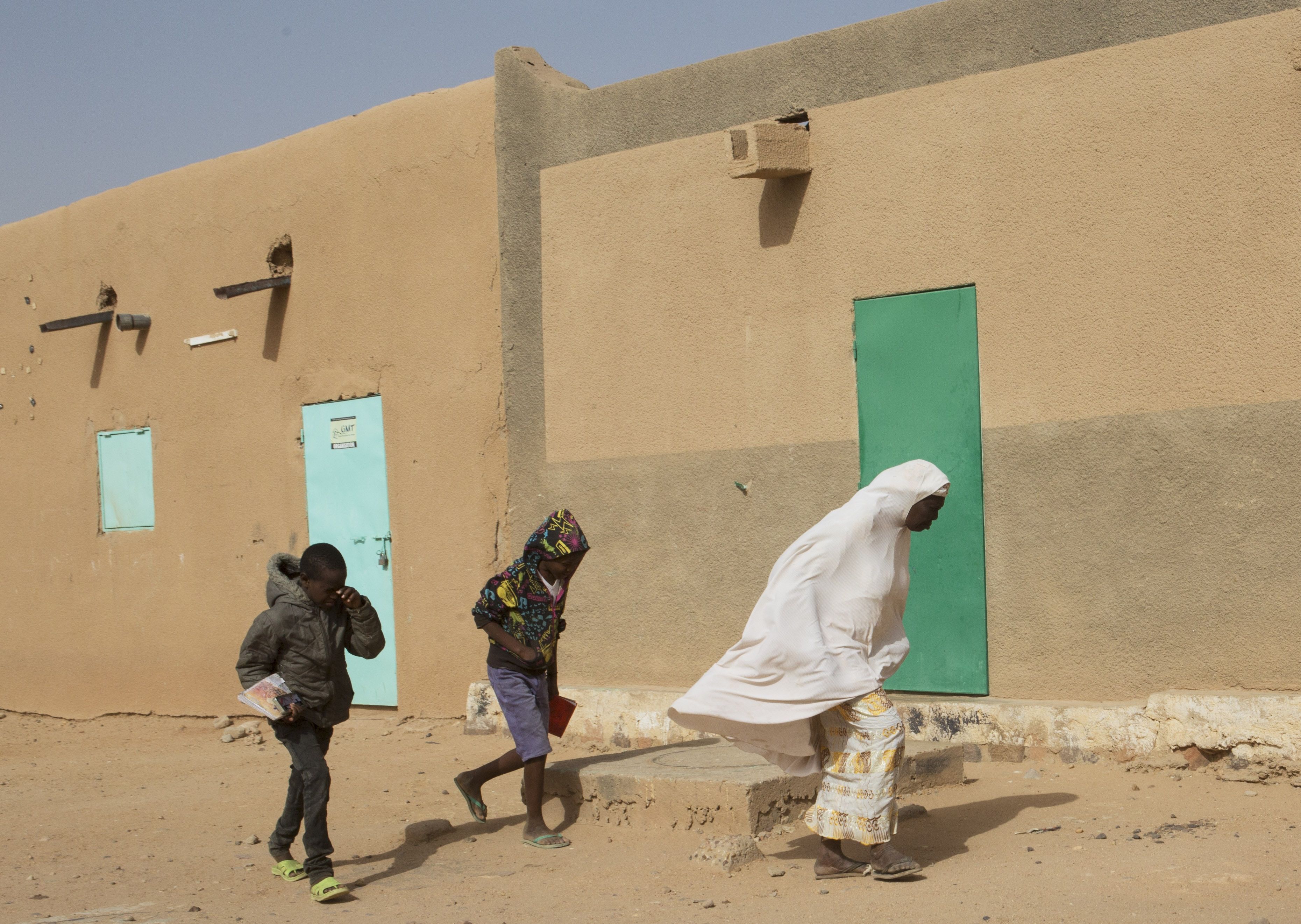 A woman and two children walk during blowing winds in Agadez, Niger, Jan. 15, 2018. Image by Joe Penney. Niger, 2018.