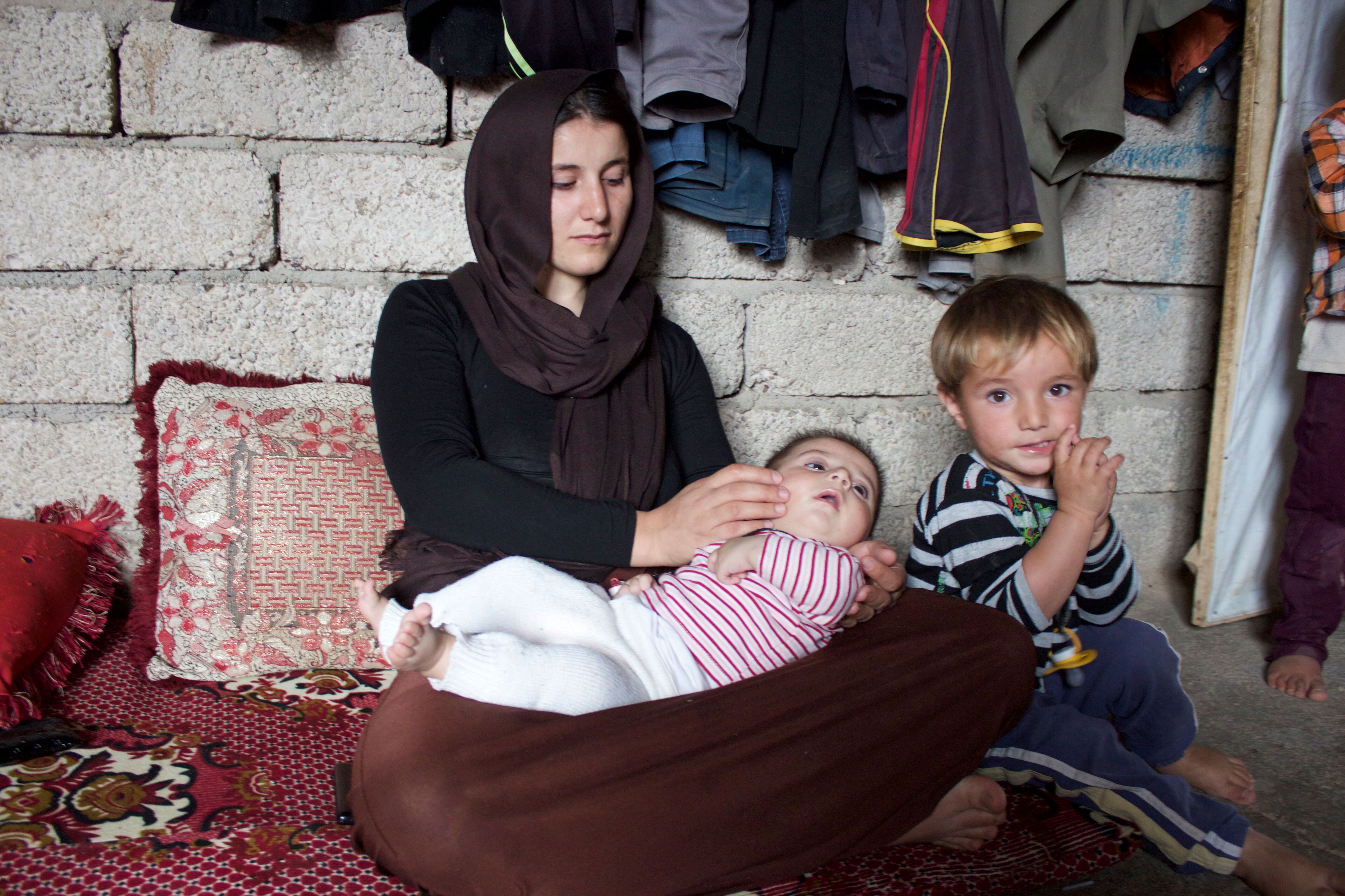 Amsha Ali Alyas cares for her sons Muiad and Delbrin in her parent’s home outside the Iraqi city of Duhok. She escaped from ISIS captivity in the summer of 2014. Image by Emily Feldman. Iraq, 2015.