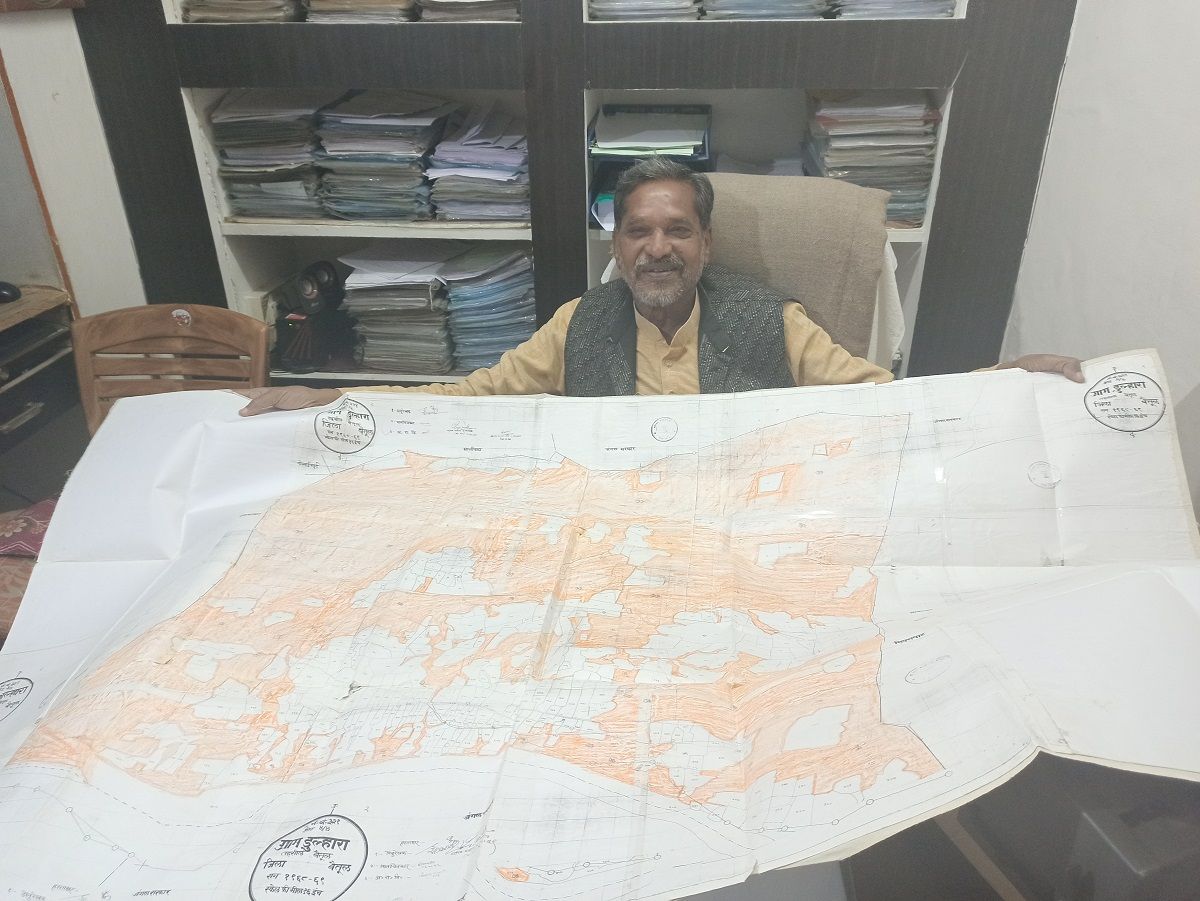 64-year old Anil Garg holds up a village map showing the extent of orange areas. He coloured the map himself. Image by Nihar Gokhale. India, undated.